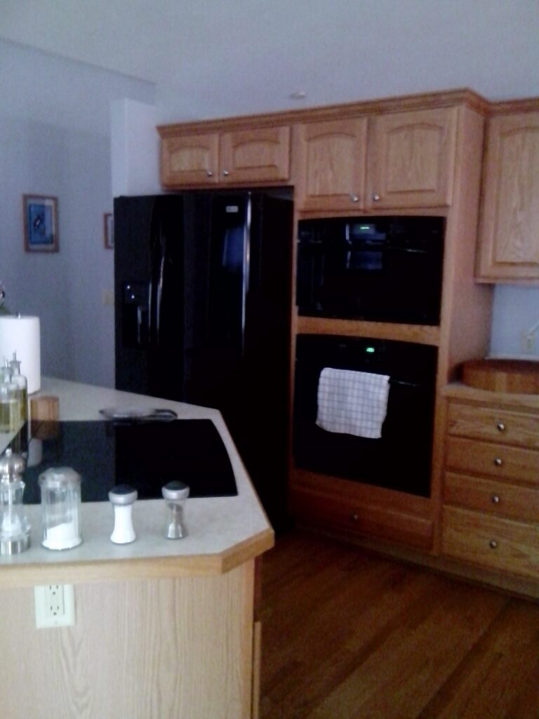 Original kitchen with light oak cabinets and black appliances before the Kitchen Express remodel