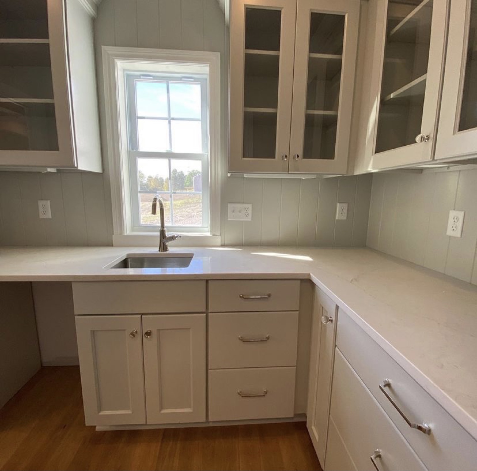 Butler's pantry with glass-front cabinets and quartz counter in a model home kitchen